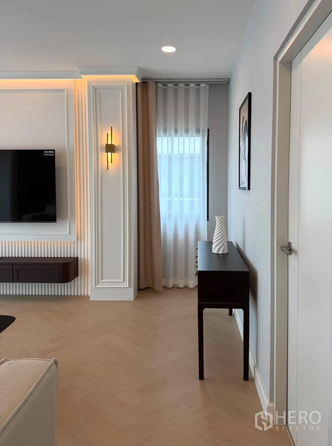 บ้านเดี่ยว for rent or sale in Bang Phli, Samut Prakan - มุมห้องนั่งเล่นพร้อมผนังทีวี โคมไฟผนัง และผ้าม่านโปร่ง