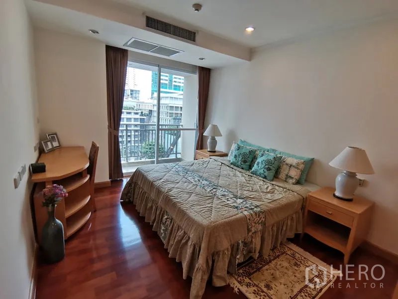 公寓 出租在Khlong Toei, Bangkok - 舒适的卧室，配有大床、床头柜、小书桌，并有推拉玻璃门通往观景阳台。