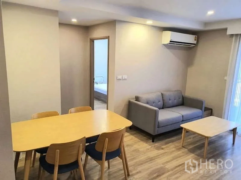 Condominium for rent in Sathon, Bangkok - Dining area for four beside a gray sofa in the living space.
