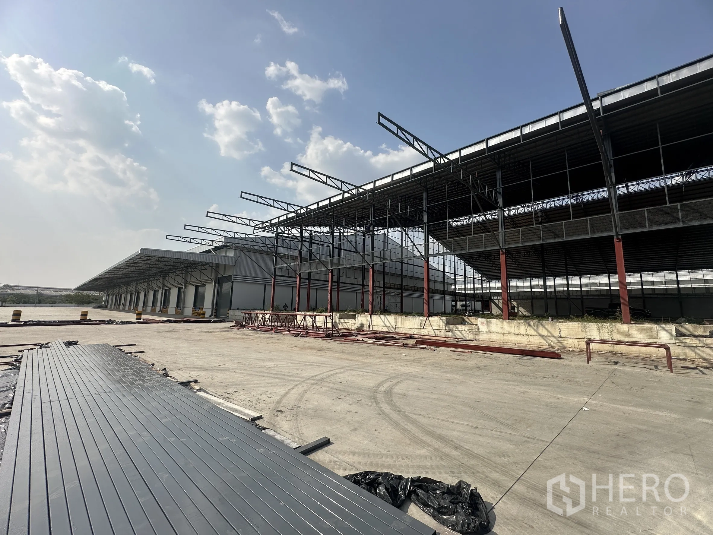 Factory for rent in Si Racha, Chon Buri - Expansive factory exterior with steel frame and long covered loading docks beside a wide concrete yard.