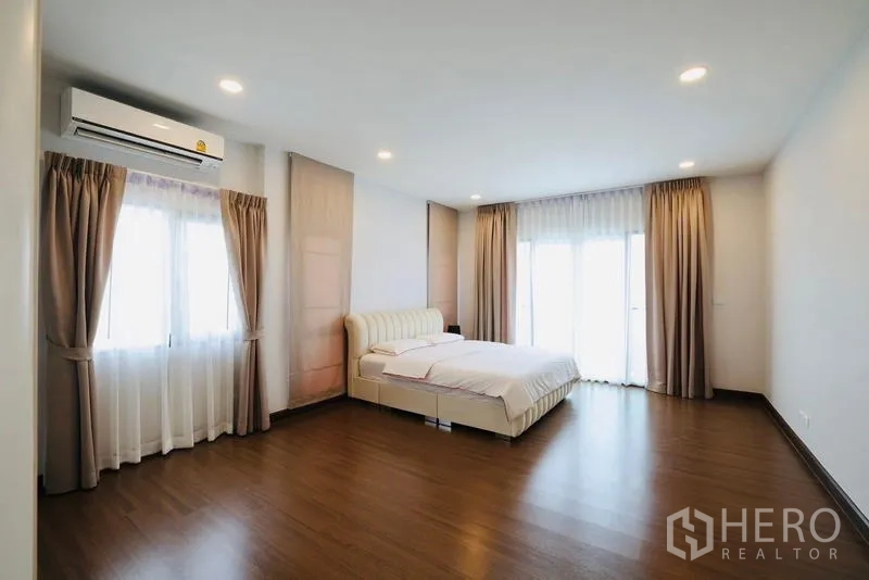 Detached House for rent in Bang Phli, Samut Prakan - Oversized master bedroom with wood floors, air-conditioning, and balcony windows.