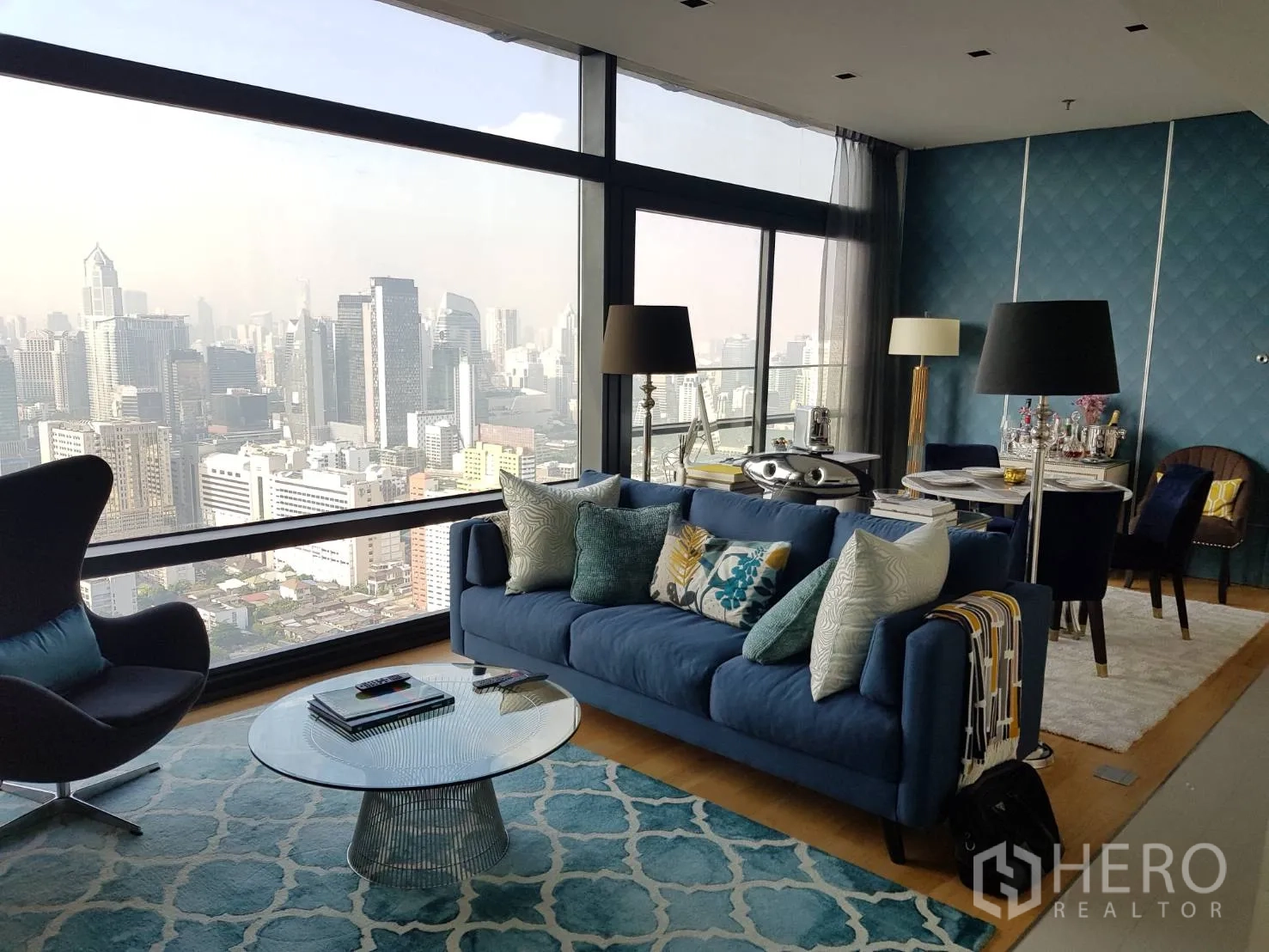 Condominium for rent or sale in Ratchathewi, Bangkok - Stylish living room with floor-to-ceiling windows and a panoramic Bangkok skyline view.