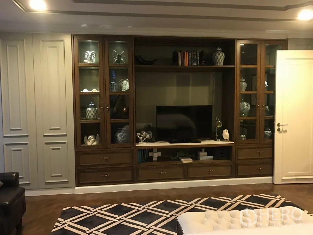 Townhouse for sale in Watthana, Bangkok - Built-in wall unit with glass display cabinets and TV in the family room.