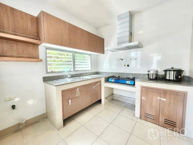 独立式住宅 出租在Prawet, Bangkok - 独立泰式厨房，木柜、窗户、炉灶、烟机与花岗岩台面。