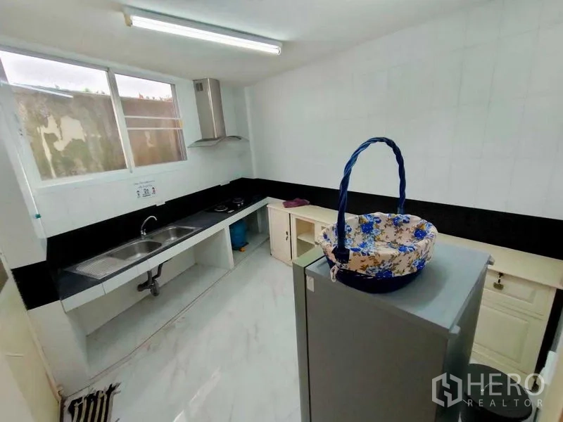 ทาวน์เฮาส์ ให้เช่าในKhlong Toei, Bangkok - ครัวบิวท์อิน มีอ่างล้างจานสองหลุม เคาน์เตอร์สีดำ เตาไฟฟ้าและเครื่องดูดควัน ใต้หน้าต่าง