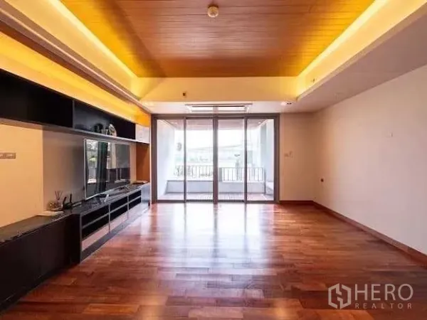Condominium for sale in Yan Nawa, Bangkok - Spacious living room with hardwood floors, recessed ceiling lighting, built‑in TV wall and sliding glass doors to a river‑view balcony at The Pano.
