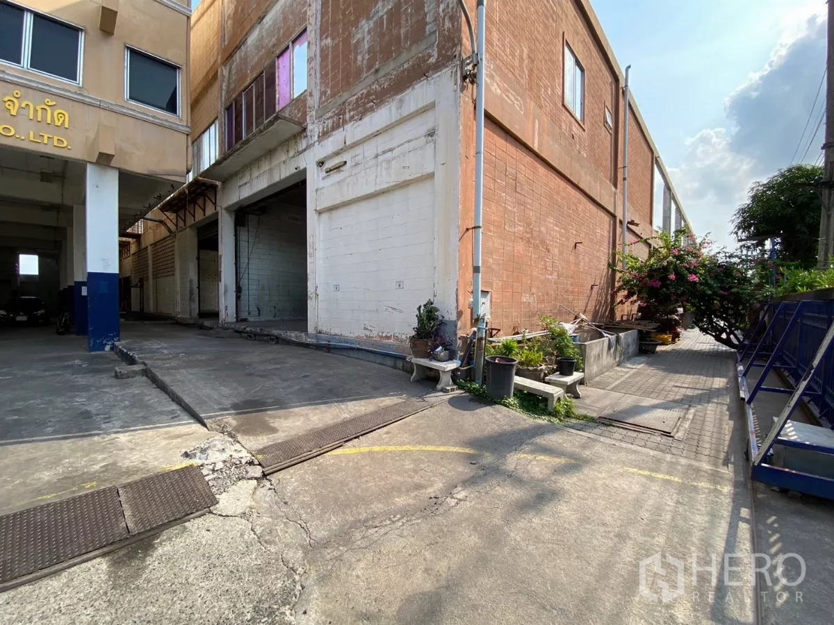 โรงงาน ขายในBang Phli, Samut Prakan - พื้นที่ช่องโหลดข้างผนังโรงงานอิฐแดง พร้อมกระบะปลูกต้นไม้เล็กๆ