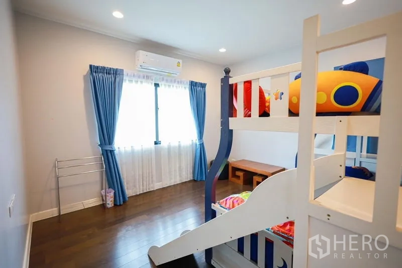 Detached House for rent or sale in Lam Luk Ka, Pathum Thani - Bright kids’ bedroom with bunk bed, blue curtains and air conditioner.