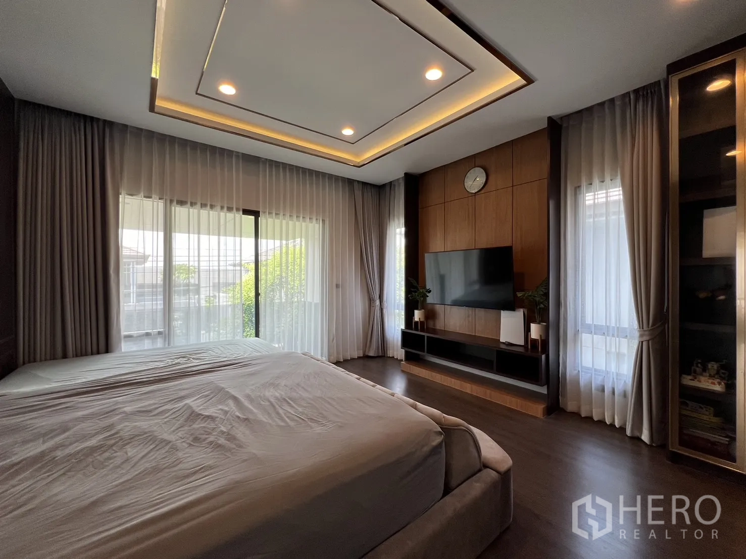Detached House for rent or sale in Bang Kapi, Bangkok - Spacious master bedroom with king bed, TV wall and balcony windows.