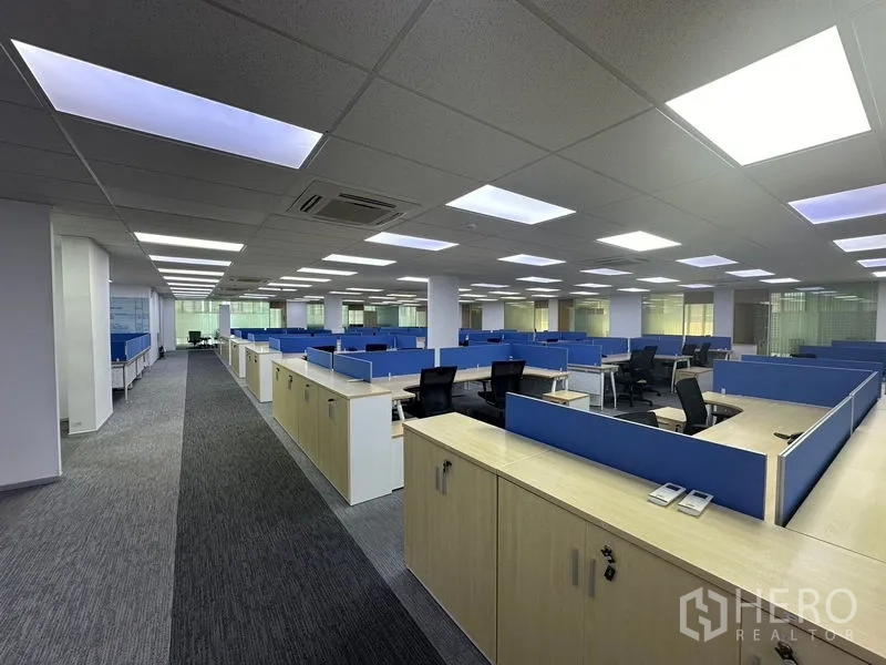 Office Space for rent - Spacious open-plan office featuring blue partitions, carpet tiles and bright ceiling lights.