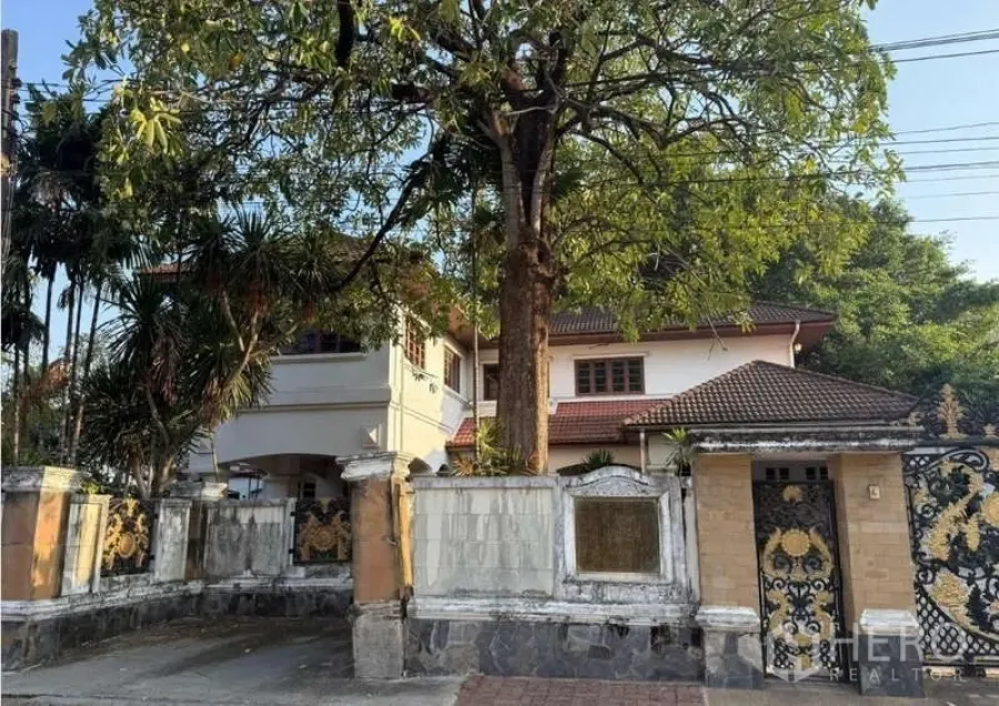 บ้าน ขายในSai Mai, Bangkok - ภาพใกล้ทางเข้าและทางรถ มีซุ้มโค้ง ระเบียงชั้นสอง และต้นไม้ใหญ่หน้าบ้านสองชั้น