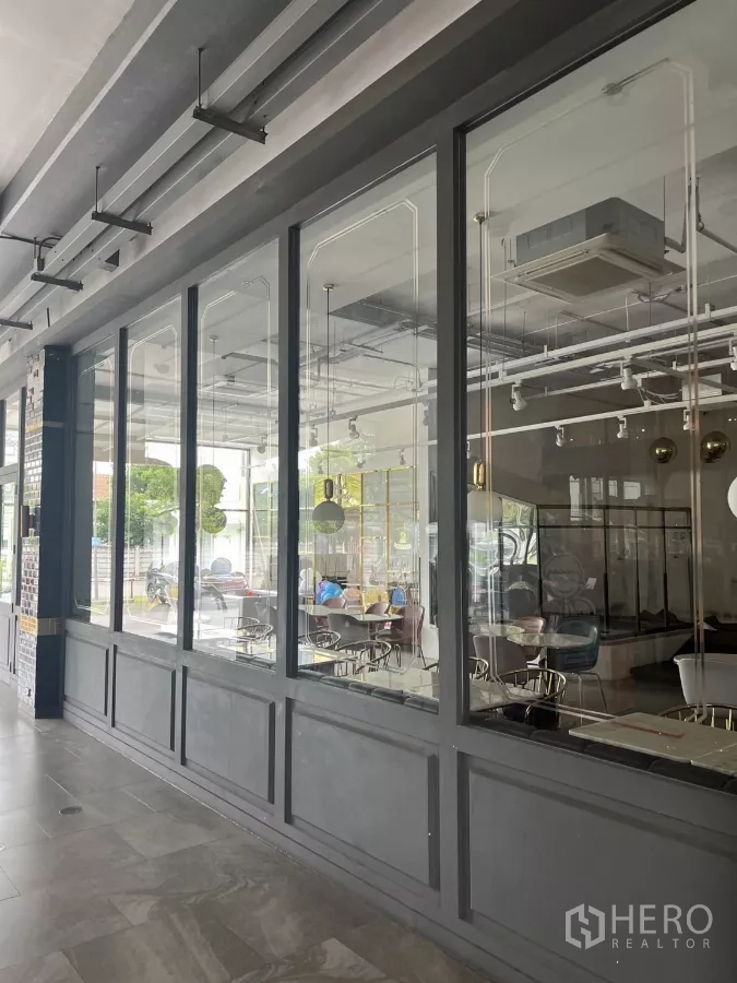 零售空间 出租在Khlong Toei, Bangkok - 落地玻璃近景，可见咖啡馆式室内与天花设备。
