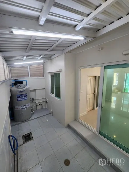 Townhouse for rent in Wang Thonglang, Bangkok - Covered utility patio with water tank, plumbing and a sliding door to the interior.