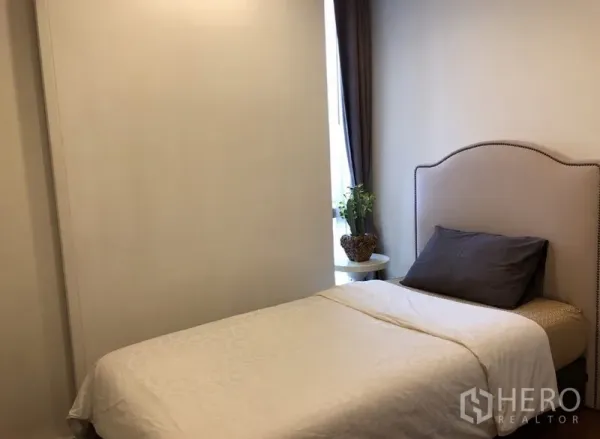 คอนโด ให้เช่าในKhlong Toei, Bangkok - ห้องนอนรองอบอุ่นพร้อมเตียงเดี่ยว โต๊ะข้าง และแสงธรรมชาติจากหน้าต่าง