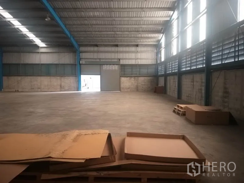 Warehouse for rent in Pathum Thani - Interior angle showing roller door, concrete slab floor, and loading area.