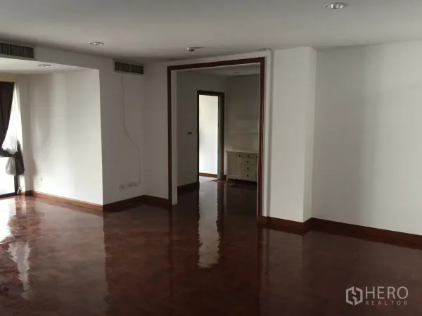 คอนโด ให้เช่าในPathum Wan, Bangkok - ห้องนั่งเล่นกว้าง พื้นปาร์เกต์เงางาม และช่องทางเปิดสู่ห้องถัดไป