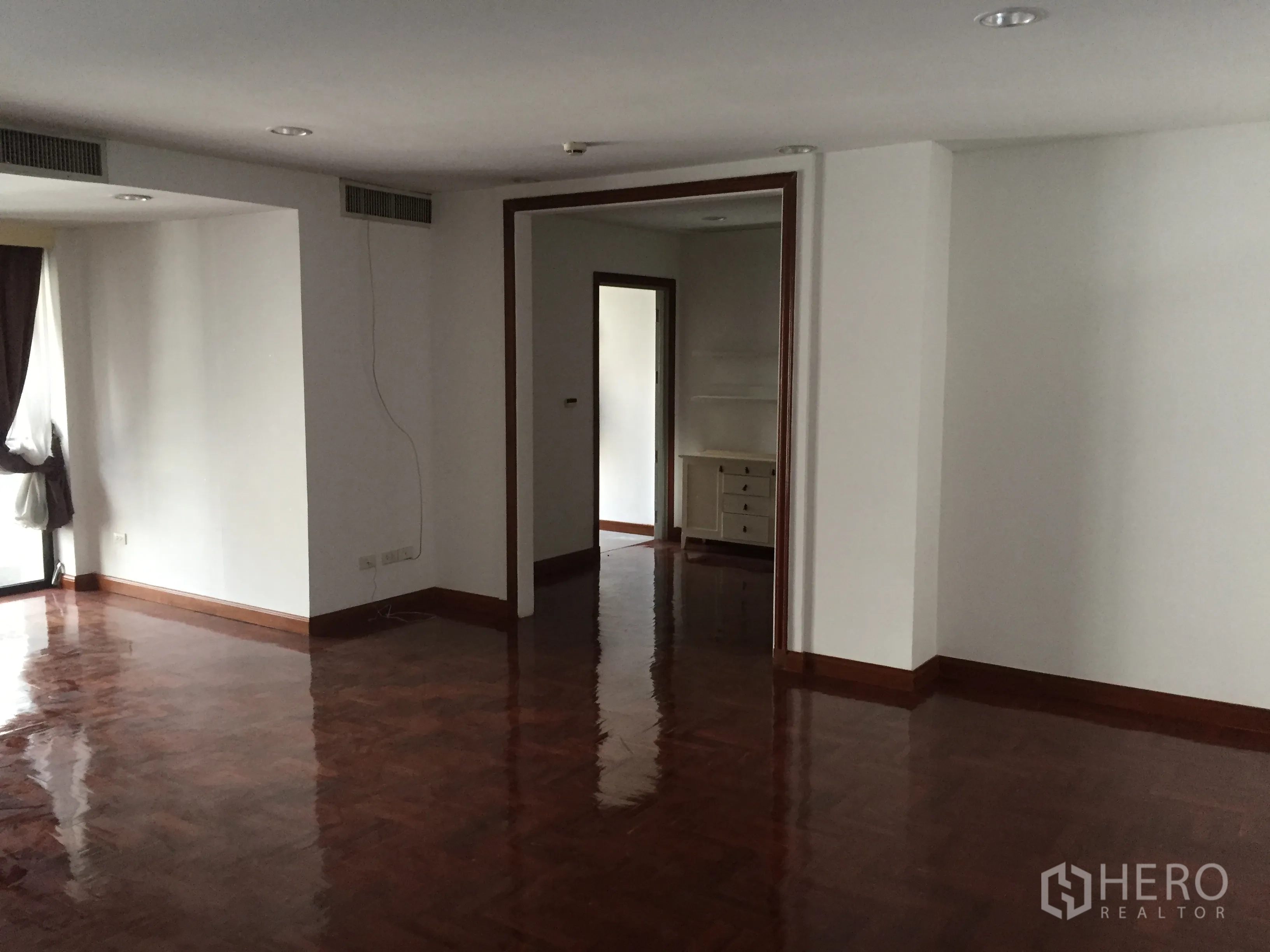 คอนโด ให้เช่าในPathum Wan, Bangkok - ห้องนั่งเล่นกว้าง พื้นปาร์เกต์เงางาม และช่องทางเปิดสู่ห้องถัดไป