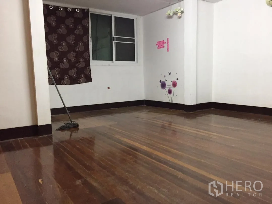 Home Office for rent or sale in Bang Khun Thian, Bangkok - Clean empty room with polished wooden floor, white walls, and a window with a curtain.