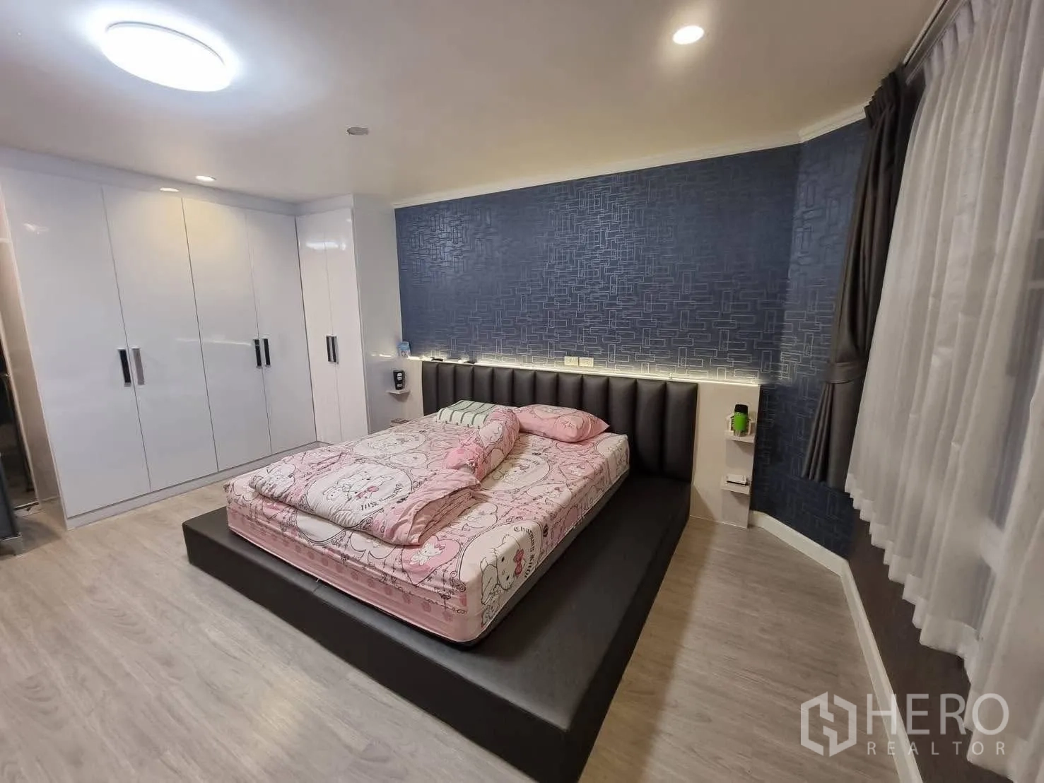 Townhouse for rent in Din Daeng, Bangkok - Master bedroom with platform bed, built-in wardrobes and feature wall.