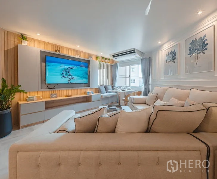 Condominium for sale in Yan Nawa, Bangkok - Modern living room angle showing TV feature wall and neutral sofas with soft lighting.
