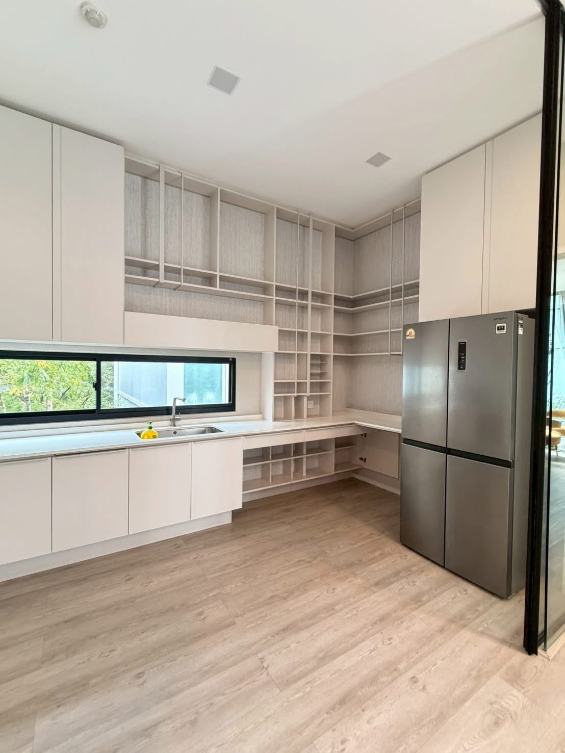 Detached House for rent in Saphan Sung, Bangkok - Bright kitchen with white cabinetry, open shelving, a wide window and large stainless refrigerator.