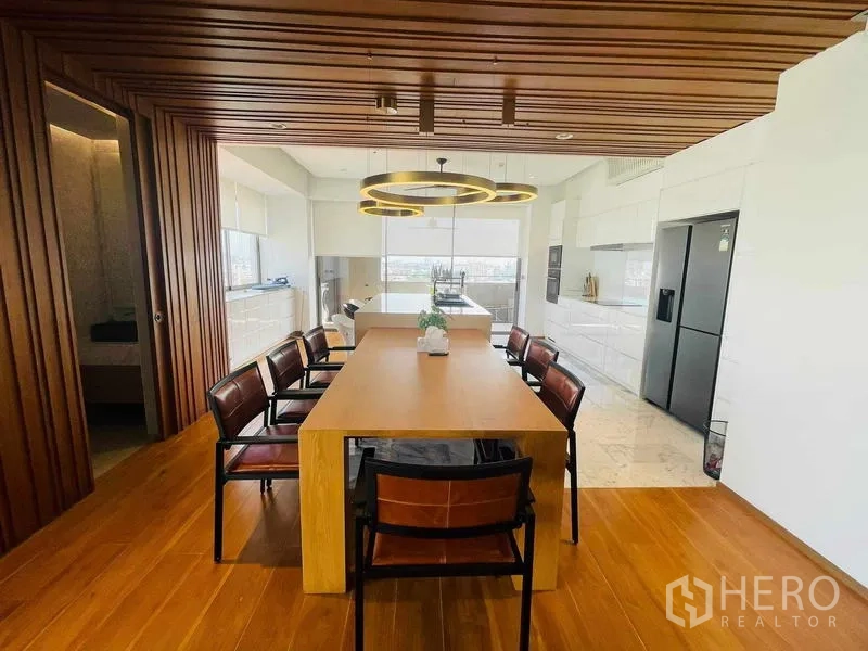 คอนโด ให้เช่าหรือขายในWatthana, Bangkok - ห้องทานอาหารโต๊ะไม้ยาวกับโคมไฟวงแหวนดีไซน์ ใกล้ครัวสว่าง