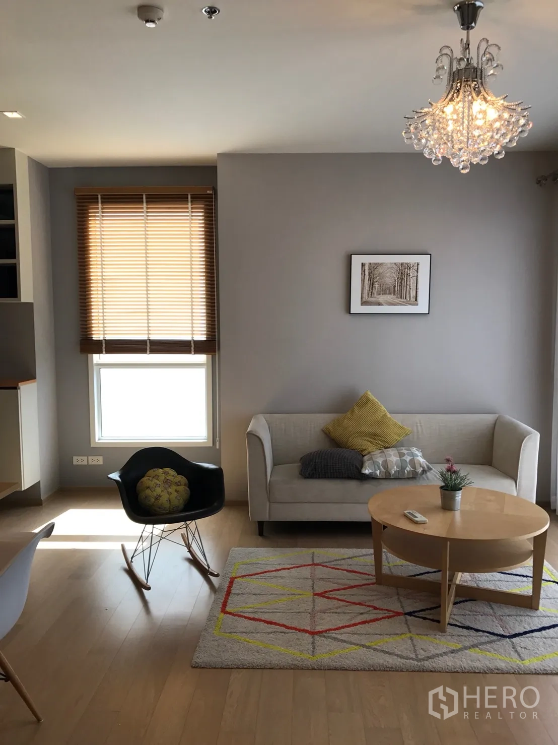 Condominium for rent or sale in Watthana, Bangkok - Living room with sofa, round coffee table, rug and crystal chandelier.