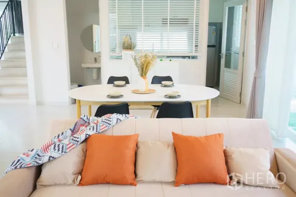 Detached House for rent in Bang Phli, Samut Prakan - Open-plan living and dining area with sofa, oval table and view to the kitchen.