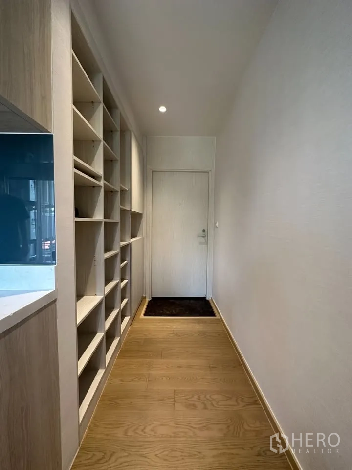 公寓 for rent in Watthana, Bangkok - 入户走廊铺木地板，整排开放式置物架通向房门。