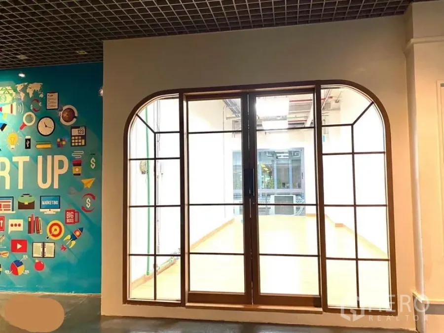 Office Space for rent in Khlong Toei, Bangkok - Hallway view of the office frontage with large arched glass doors beside a colorful mural.