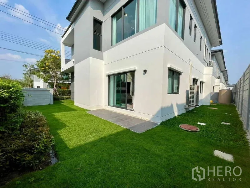 Detached House for rent in Bang Phli, Samut Prakan - Side and rear yard with green lawn and a small tiled patio by the sliding door.