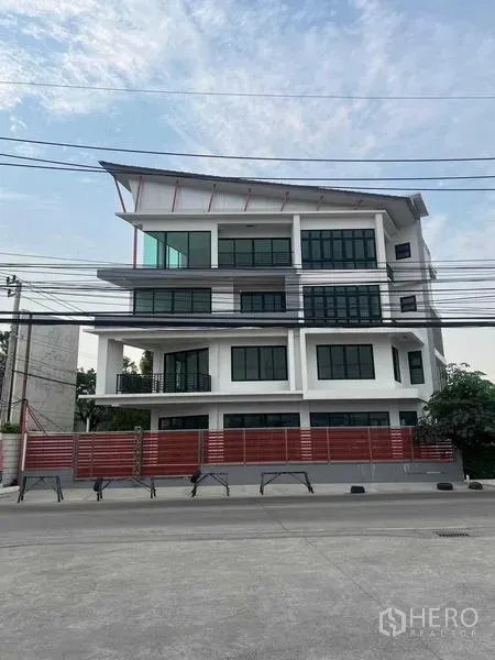 สำนักงานที่บ้าน ให้เช่าในBang Kruai, Nonthaburi - โฮมออฟฟิศสมัยใหม่หลายชั้น กระจกรอบอาคารและรั้วสีแดง มุมมองจากถนนในบางกรวย