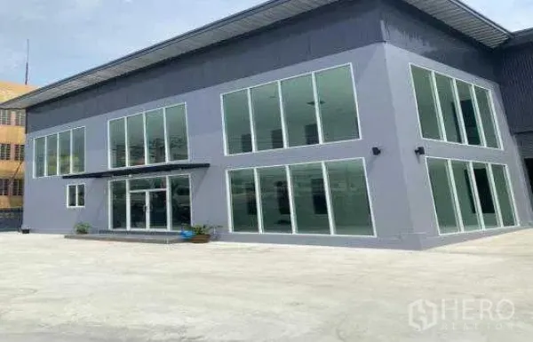 货栈 出租在Prawet, Bangkok - 两层落地玻璃办公楼与仓库相连，前方设有宽阔混凝土场地。