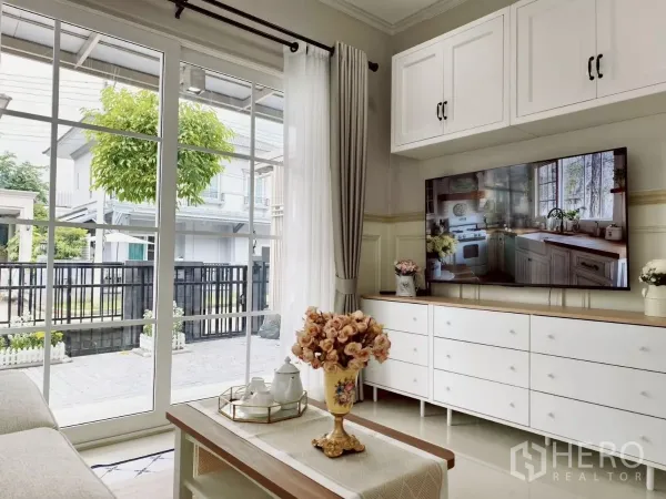 独立式住宅 出租在Khlong Luang, Pathum Thani - 客厅带电视柜与茶几，对望落地玻璃门与庭院