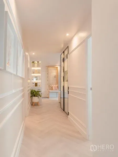Condominium for sale in Yan Nawa, Bangkok - Light-filled corridor with decorative wall molding and glass partition leading to bedrooms.