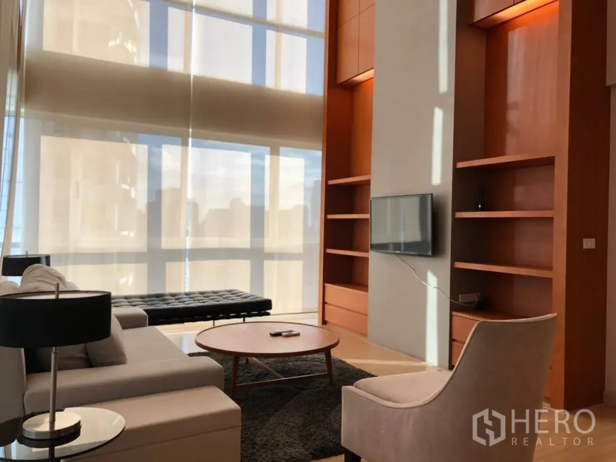 คอนโด ให้เช่าในPathum Wan, Bangkok - ห้องนั่งเล่นสว่าง เพดานสูง กระจกเต็มบาน พร้อมชั้นบิลท์อินและโซฟา