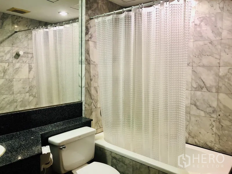 คอนโด ให้เช่าในPathum Wan, Bangkok - ห้องน้ำปูกระเบื้องลายหินอ่อนพร้อมอ่างอาบน้ำ ม่านอาบน้ำ และกระจกบานใหญ่