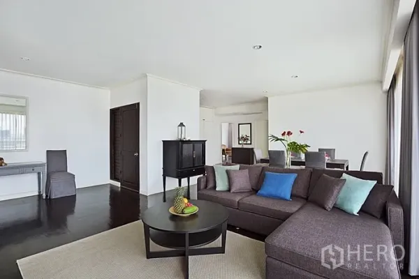 Condominium for rent in Khlong San, Bangkok - Spacious living room with L-shaped sofa, coffee table and wide city-view windows.