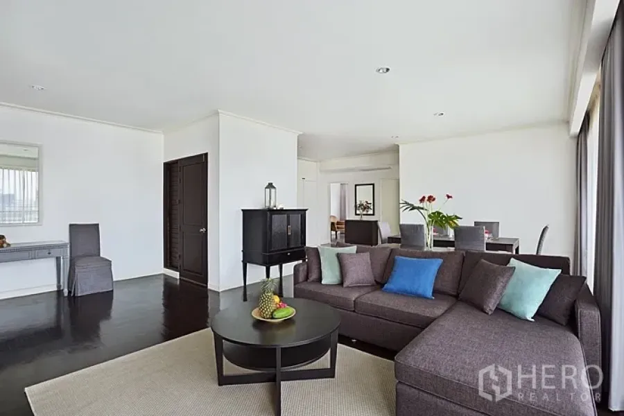 Condominium for rent in Khlong San, Bangkok - Spacious living room with L-shaped sofa, coffee table and wide city-view windows.