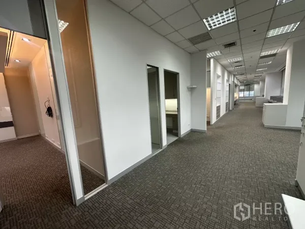 办公空间 出租在Watthana, Bangkok - 长走廊连接多间房，玻璃隔断与地毯地面。