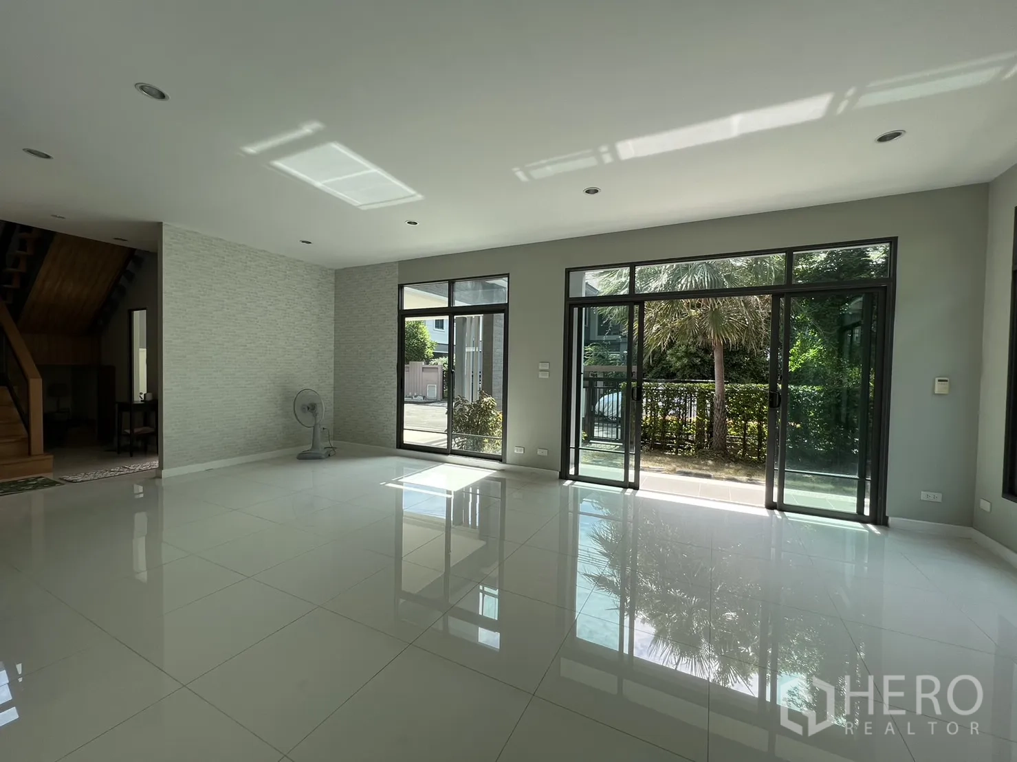 Detached House for sale in Suan Luang, Bangkok - Living area showing staircase and multiple glass doors bringing natural light.