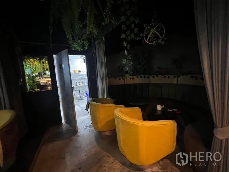 零售空间 出租在Watthana, Bangkok - 昏暗的休息室，黄色扶手椅、圆桌与帘幕分隔。