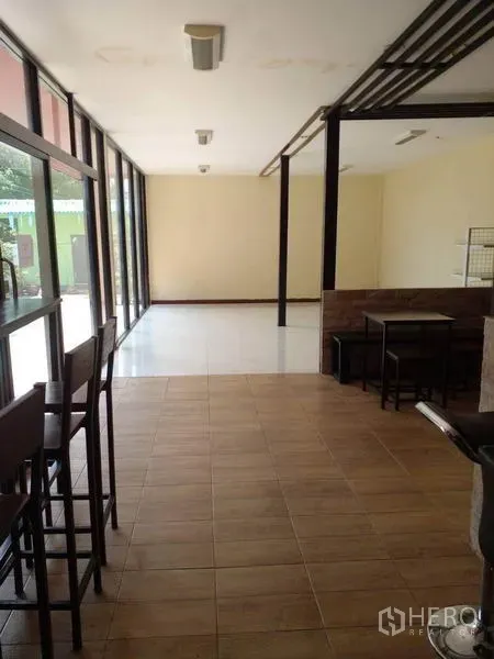 Shophouse for sale in Lam Luk Ka, Pathum Thani - Open-plan hall with large windows, mixed tile floors and seating.