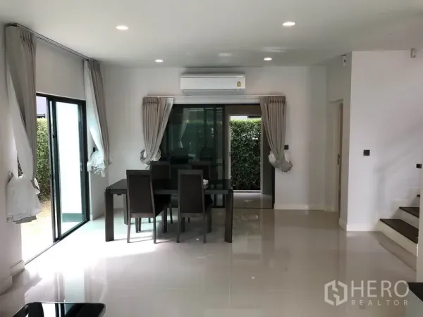 Detached House for rent or sale in Bang Kapi, Bangkok - Open-plan dining area with sliding glass doors, air conditioning and a staircase.