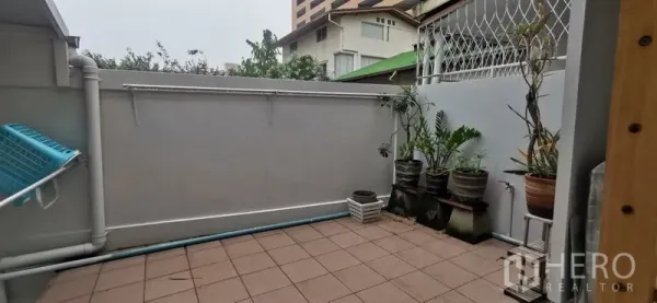 Townhouse for rent in Watthana, Bangkok - Private tiled terrace with potted plants and utility area