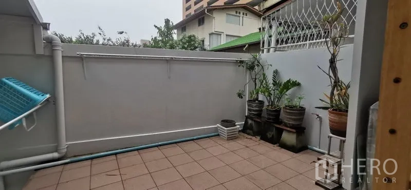 Townhouse for rent in Watthana, Bangkok - Private tiled terrace with potted plants and utility area