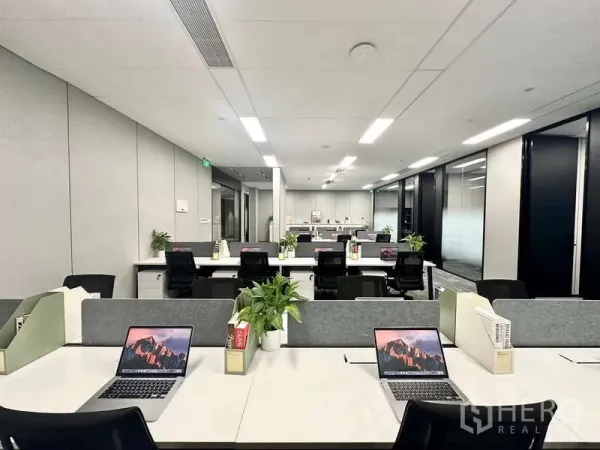 สำนักงาน ให้เช่าในBang Kapi, Bangkok - สำนักงานแบบเปิดโล่ง โต๊ะทำงานเรียงเป็นแถว พร้อมโน้ตบุ๊กและกระถางต้นไม้ ใต้ไฟ LED