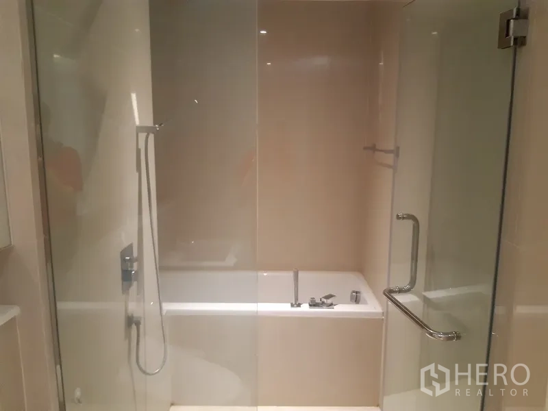 Condominium for rent or sale in Watthana, Bangkok - Glass-enclosed shower with separate bathtub in a neutral-tiled bathroom.