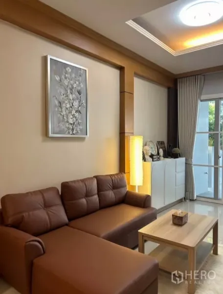Townhouse for rent in Wang Thonglang, Bangkok - Cozy corner with brown sectional sofa, floor lamp and wall art