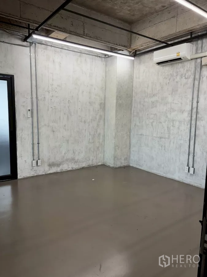Office Space for rent in Watthana, Bangkok - Small enclosed room with concrete walls, linear LEDs and a wall-mounted air conditioner.